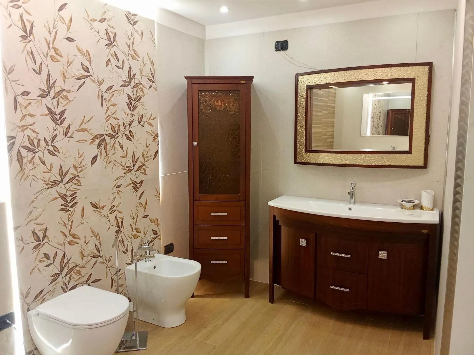 Bagno moderno con WC, bidet, mobiletto in legno, lavabo con mobiletto e ampio specchio.