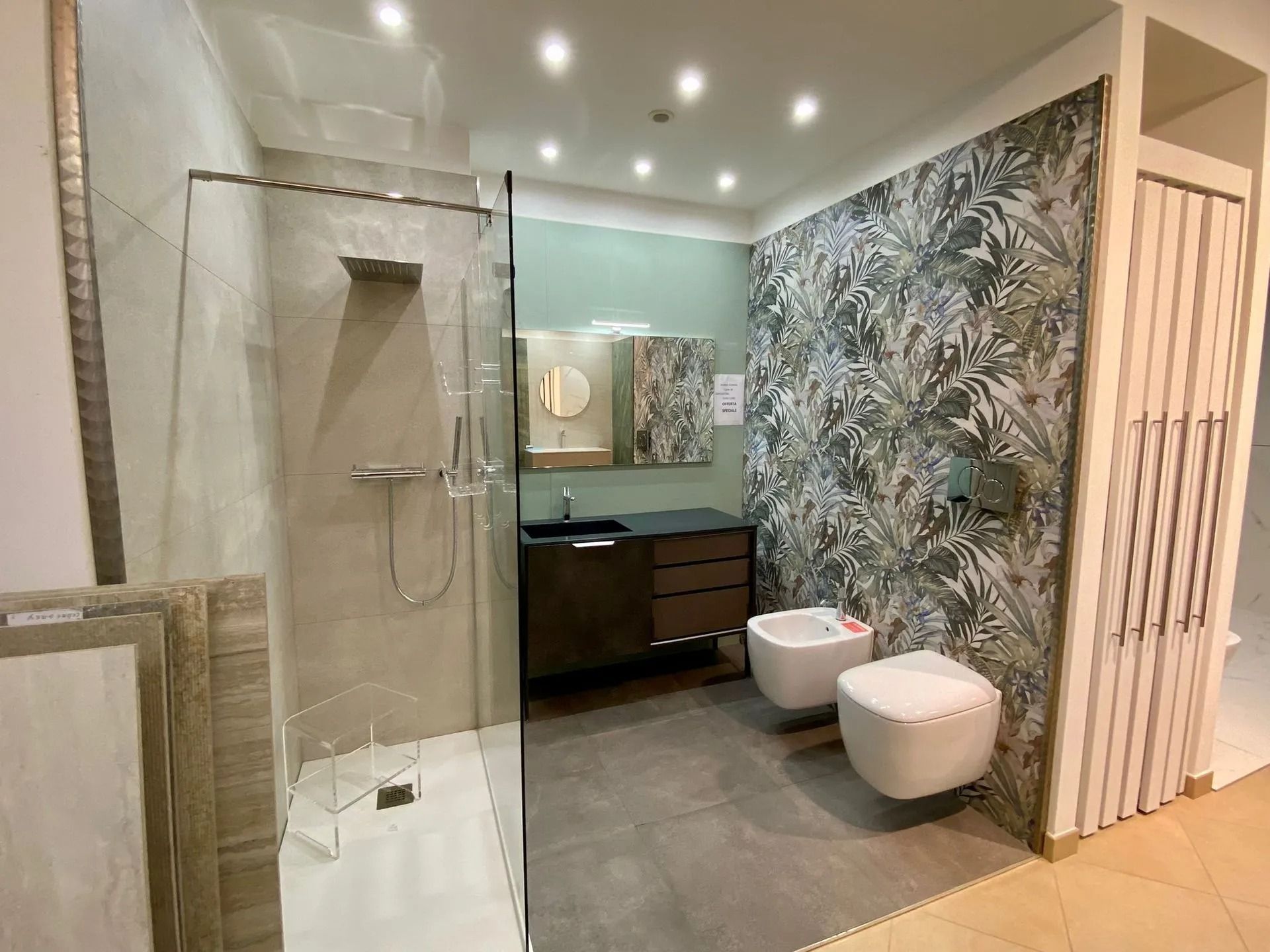 Bagno moderno con doccia in vetro, mobile bagno con doppio lavabo e parete decorata con motivi floreali.