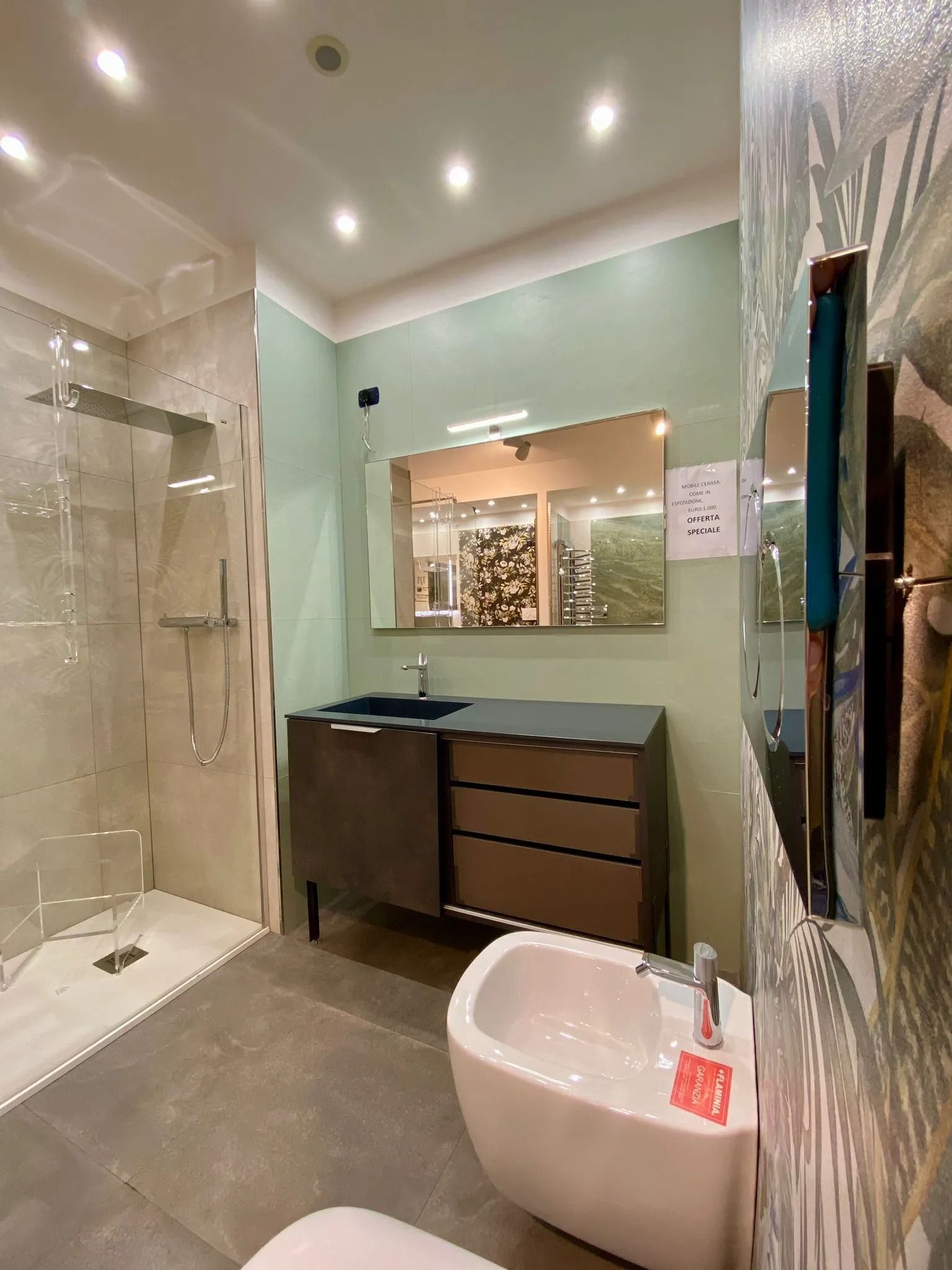 Bagno moderno con doccia in vetro, mobile sospeso, specchio rotondo e lavabo a ciotola bianco.
