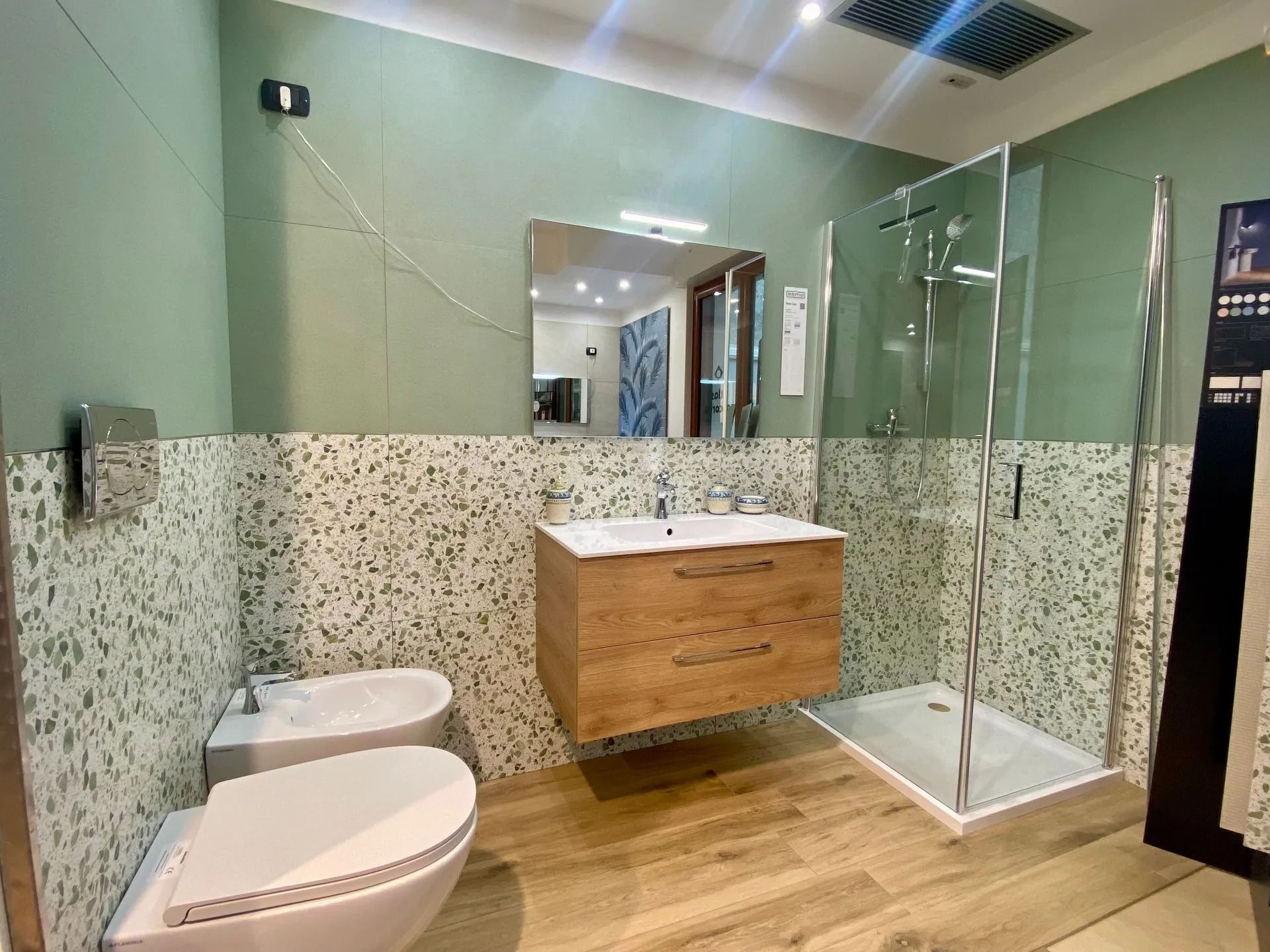 Bagno moderno con mobiletto in legno, doppio lavabo, WC e doccia con box in vetro.