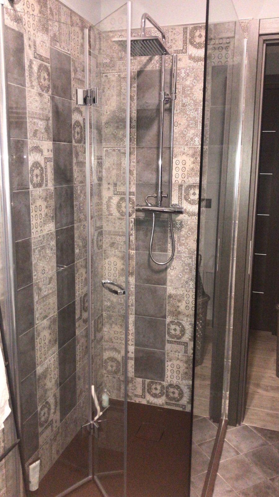 Box doccia con porte in vetro, pareti piastrellate in un ambiente bagno.