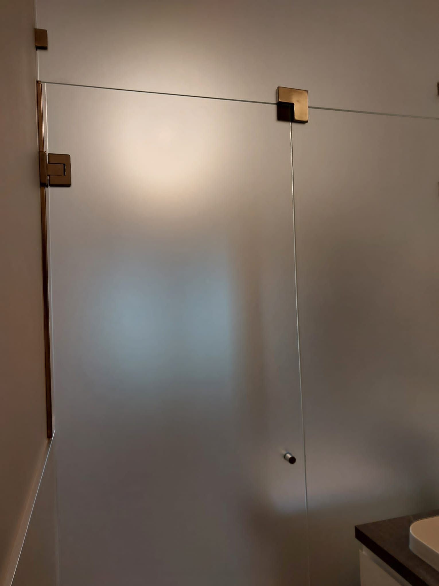 Porta doccia in vetro satinato con ferramenta dorata. Interno del bagno.