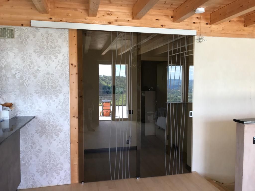 Porte scorrevoli in vetro con linee verticali che conducono a una stanza con vista.