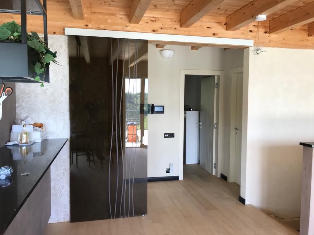 Porta scorrevole in vetro marrone in una cucina moderna. Porta aperta sul corridoio ed elettrodomestici bianchi.