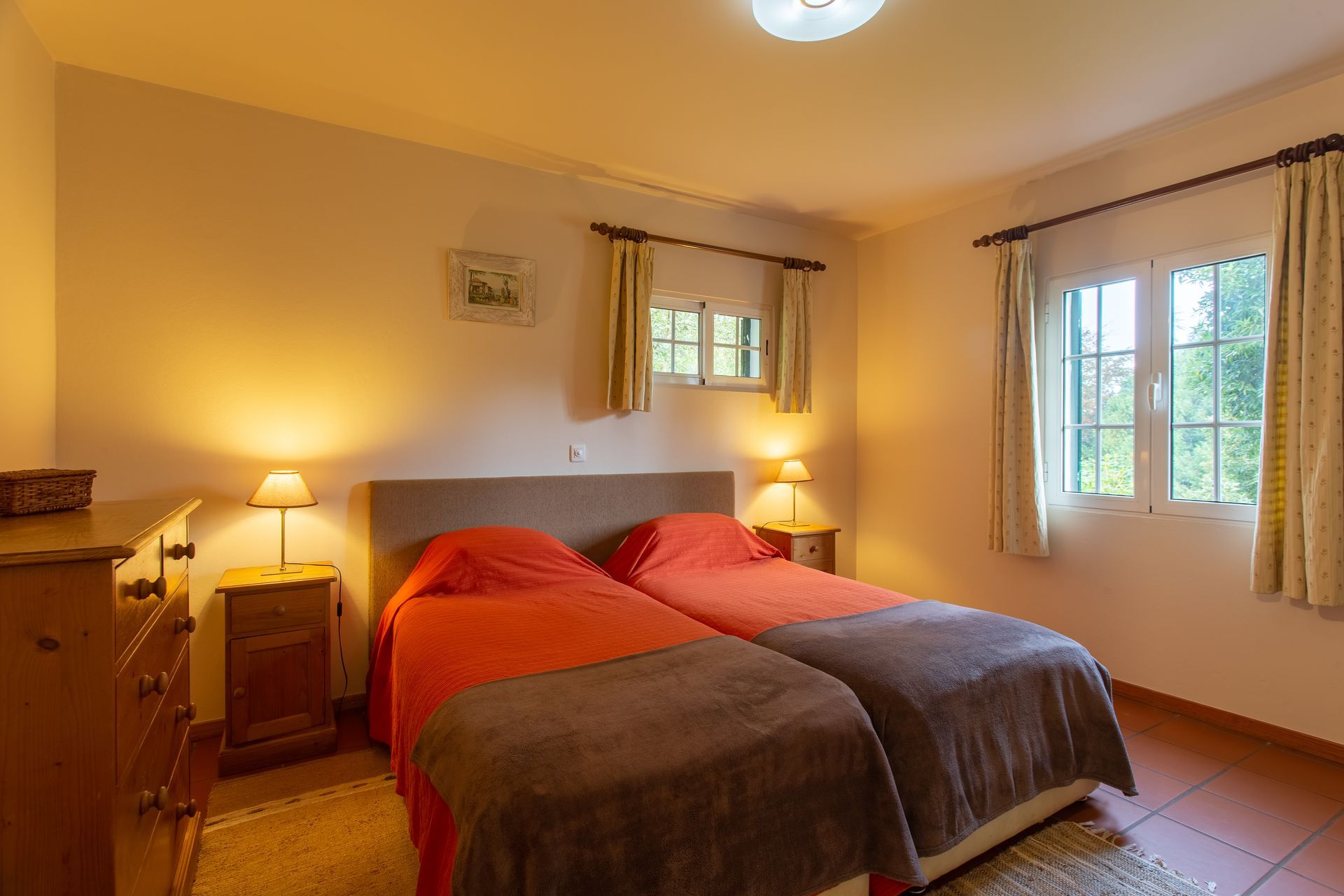 Bedroom with two twin beds, orange/gray bedding, nightstands, and a window.