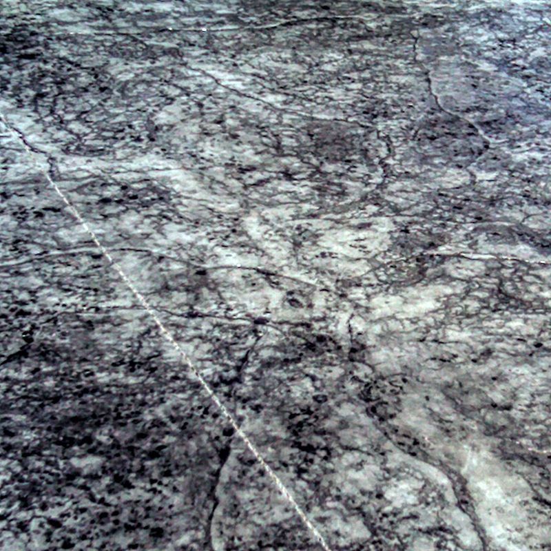 Gray and white marbled stone surface with dark veins and a diagonal light streak