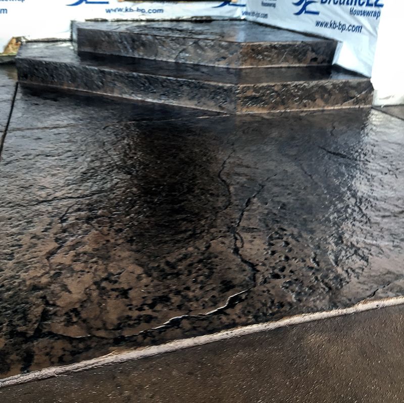 Black rubberized ramp and wet floor in front of tiered concrete steps