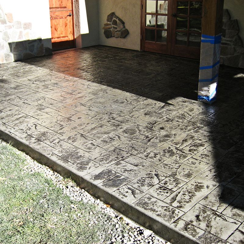 Covered porch with patterned tile floor, sunlight and shadows, and a wrapped support column near a doorway