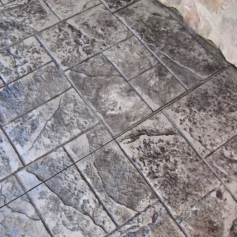 Stone-tiled floor with irregular gray slabs and dark grout lines next to a stone wall