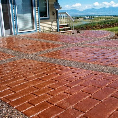 Wet red brick patio beside a house, with mountains and blue sky in the distance.