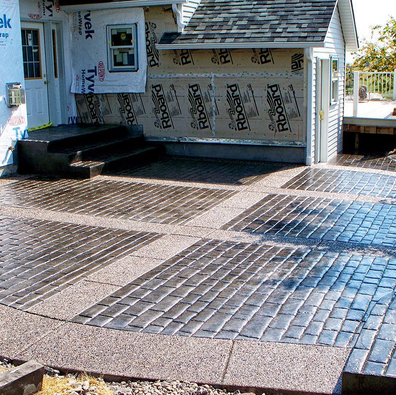 Brick-patterned accessibility ramp and walkway outside a building entrance with steps and graffiti-covered walls