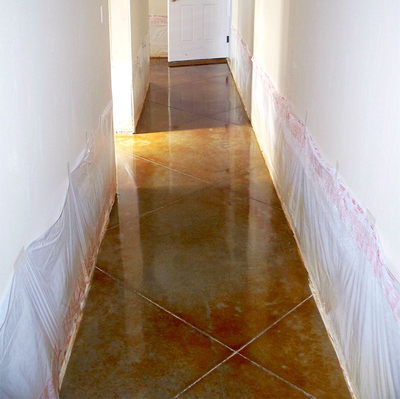 Narrow hallway with glossy brown tile floor and white walls under renovation.