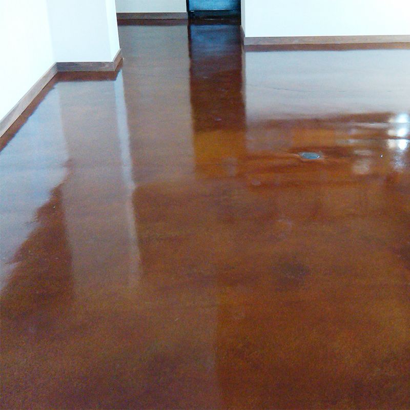 Empty room with a glossy brown floor and white walls, reflecting light from a doorway.