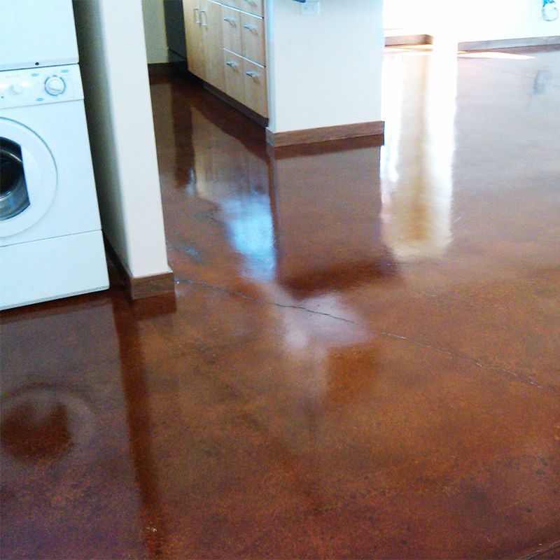Shiny brown kitchen floor with a washing machine on the left and cabinets in the background