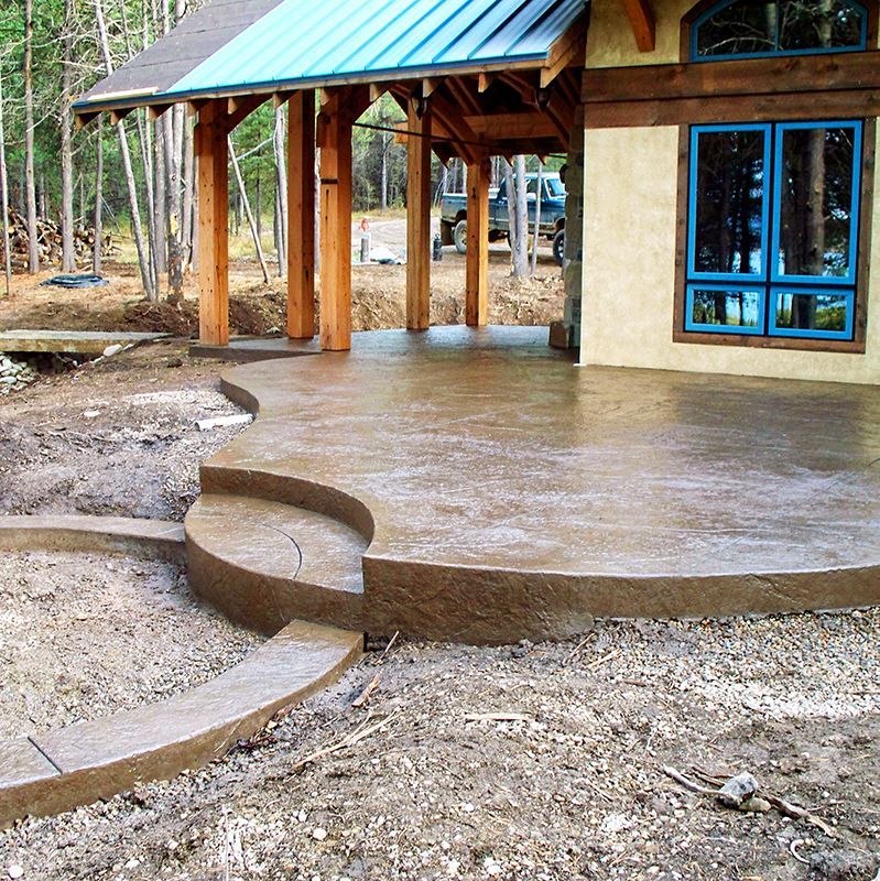 House with curved concrete patio and steps in a muddy, unfinished yard