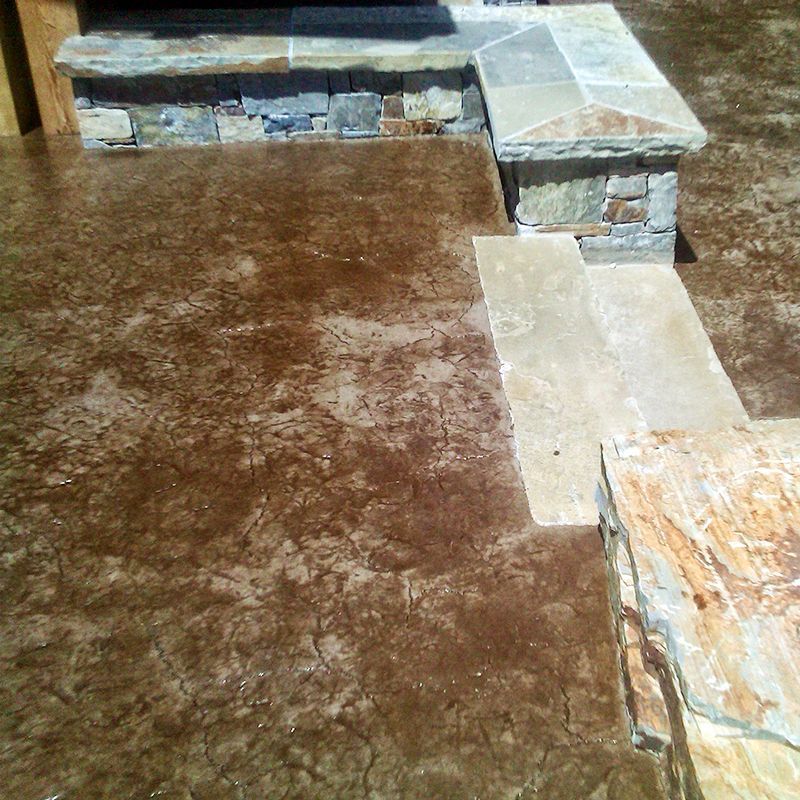 Stone steps and a tiled ledge beside a brown concrete patio floor.