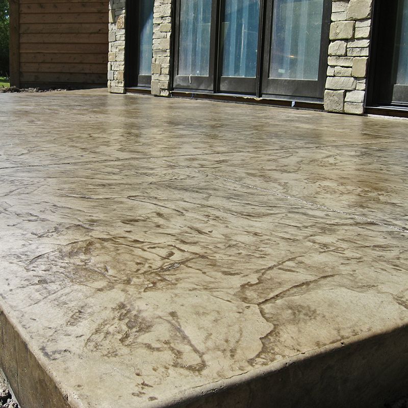 Stone patio beside glass doors and stone wall in bright sunlight