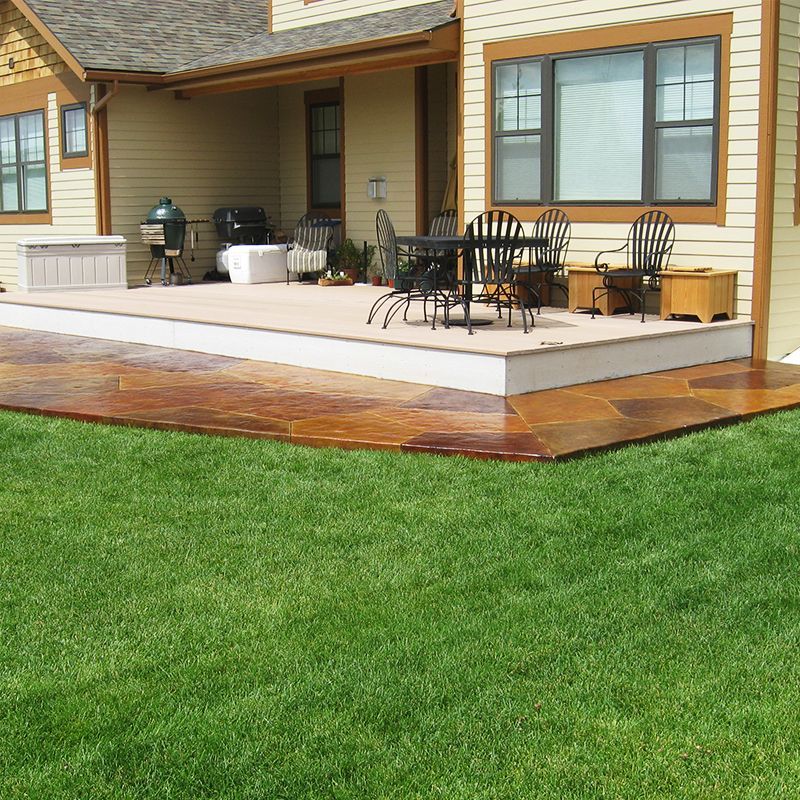 Back porch with patio furniture, wooden deck, and green lawn in front of a house