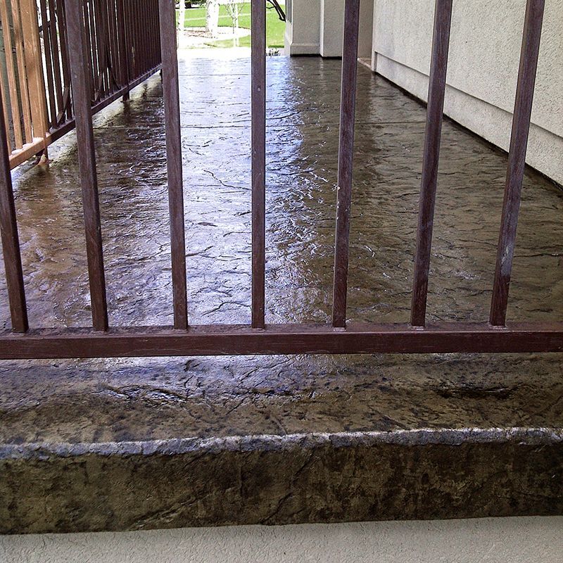 Wet concrete floor behind metal bars in a covered walkway