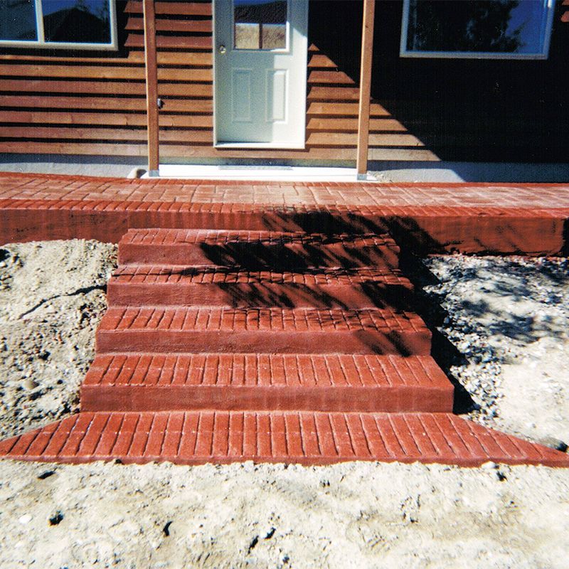 Red brick steps leading to a white front door with a porch and wooden exterior siding