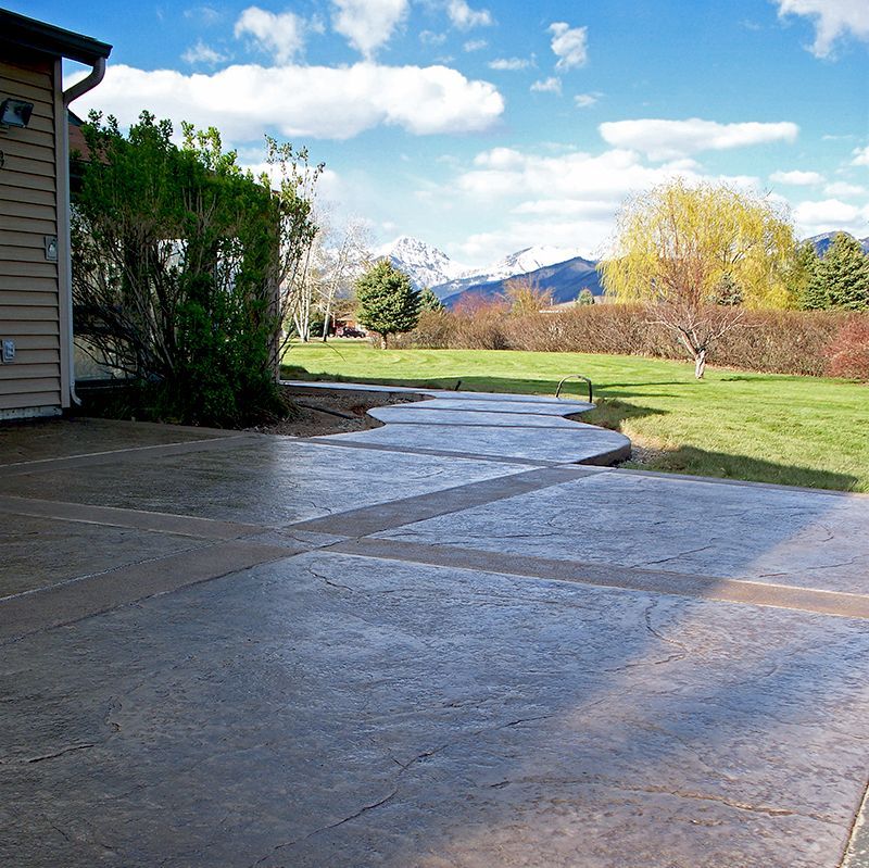 Backyard patio and lawn with mountains in the distance under a partly cloudy sky