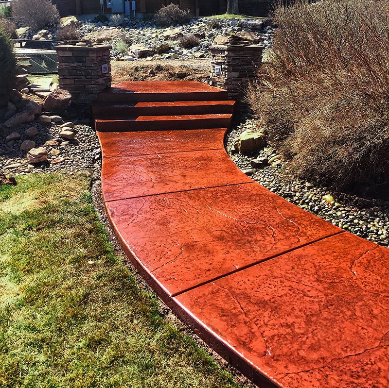 Curved red walkway leading to brick steps in a landscaped garden