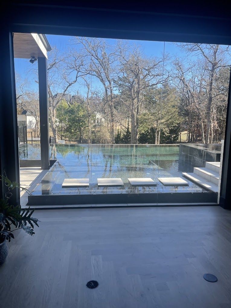 A large window with a view of a swimming pool and trees.
