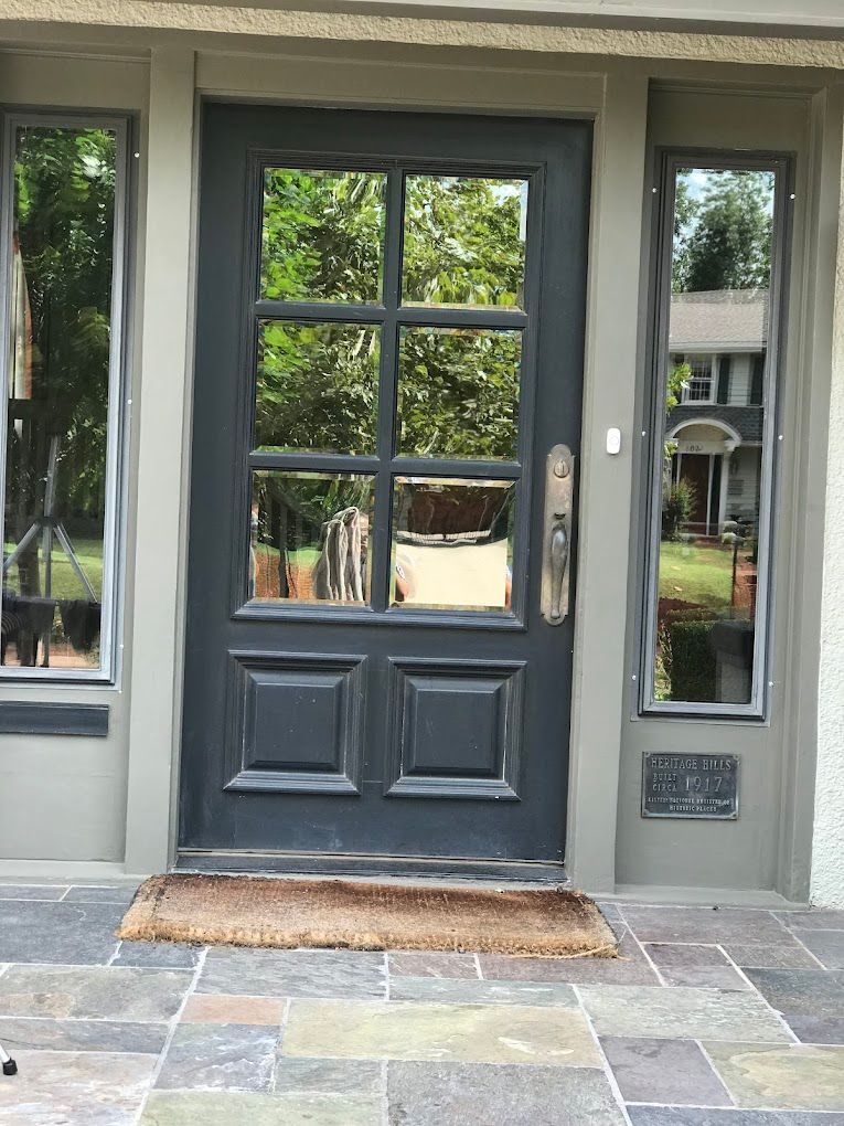 The front door of a house with a black door and windows.