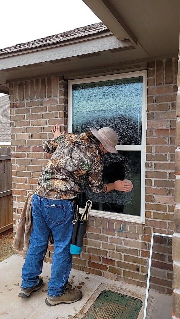 A man is cleaning a window on a brick building.