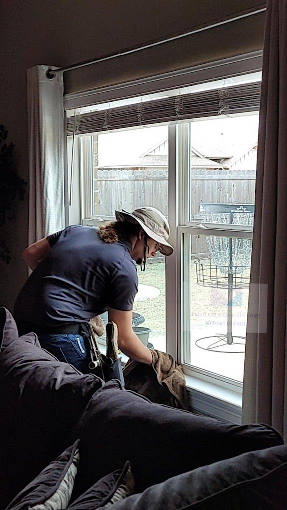A man is cleaning a window in a living room.