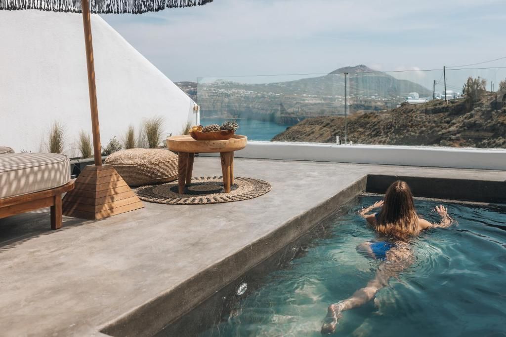 Woman swimming in a pool on a patio, with ocean and mountains visible in the background.