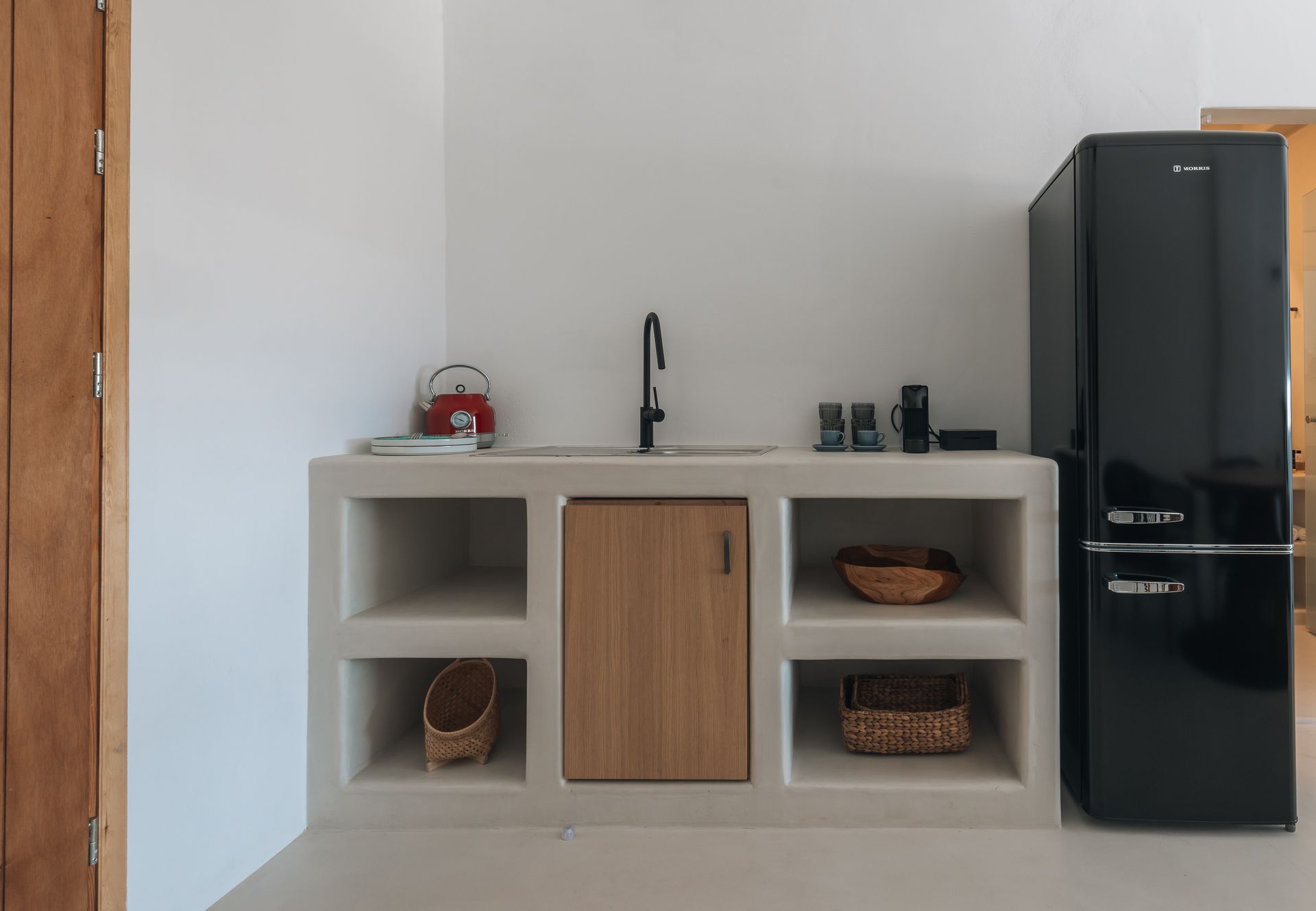 White kitchen with a black refrigerator, sink, and wooden cabinet.