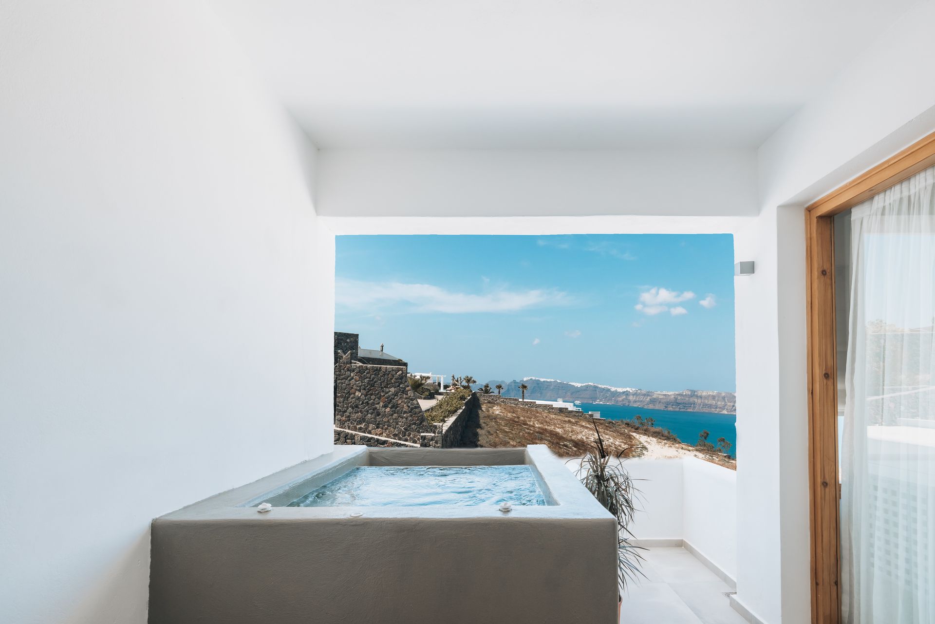 Outdoor jacuzzi overlooking a scenic ocean view on a sunny day.