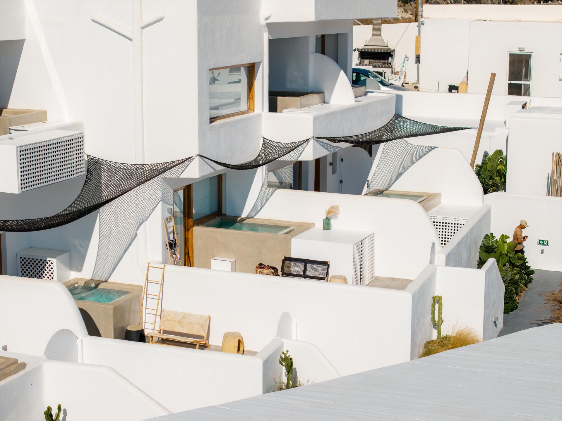 White buildings with terraces and net canopies, likely in a sunny, Mediterranean setting.