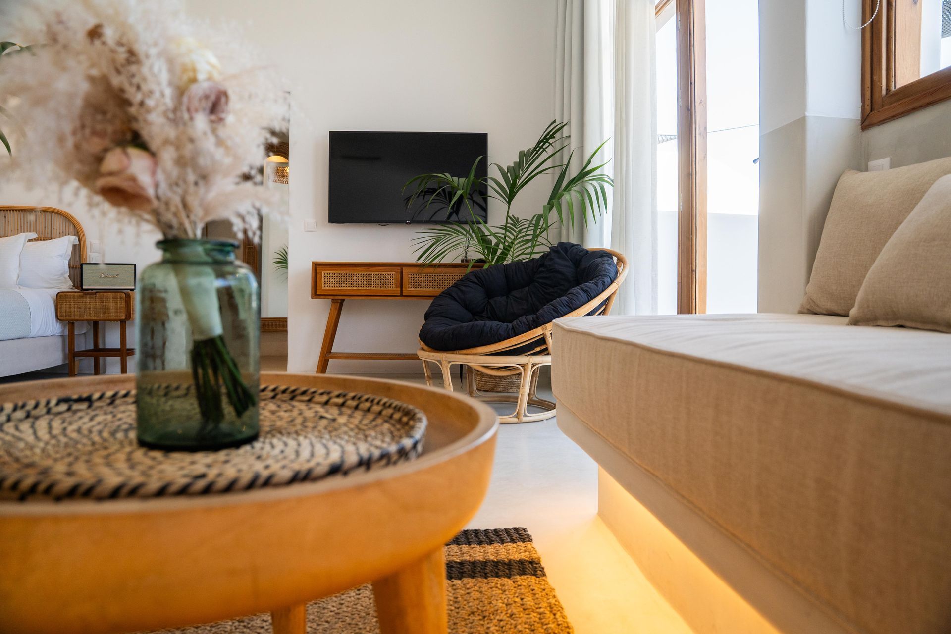 Cozy living room with neutral tones, a circular chair, and a glass vase on a wooden coffee table.