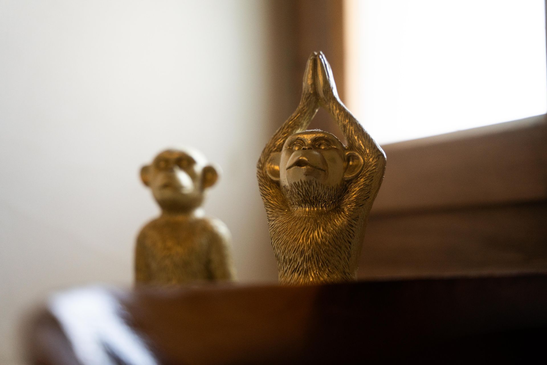 Two golden monkey figurines: one seated, the other with hands raised in prayer.