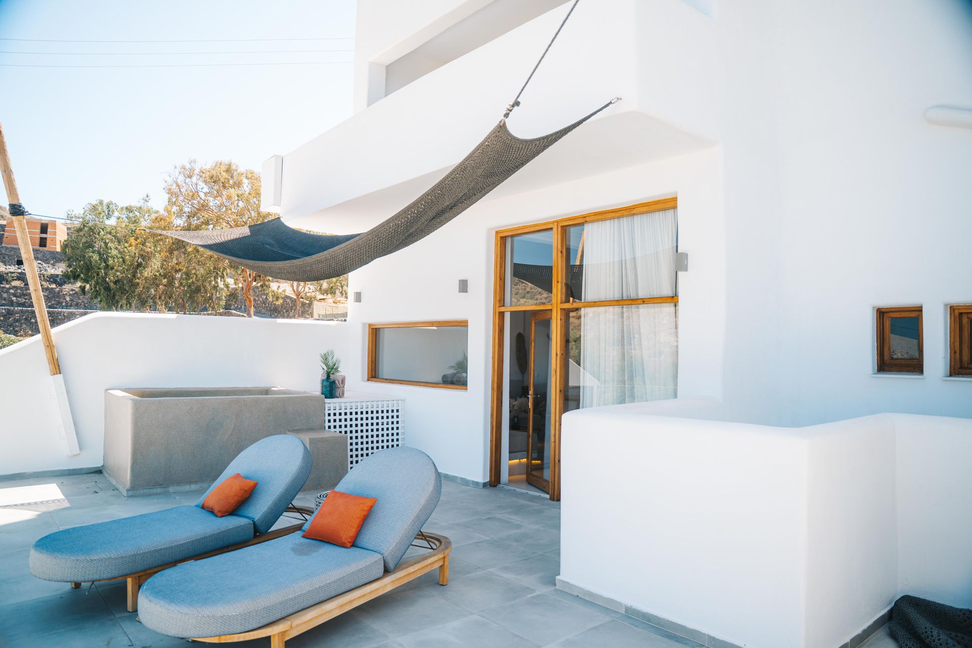 Two blue lounge chairs on a white patio with a shaded area.