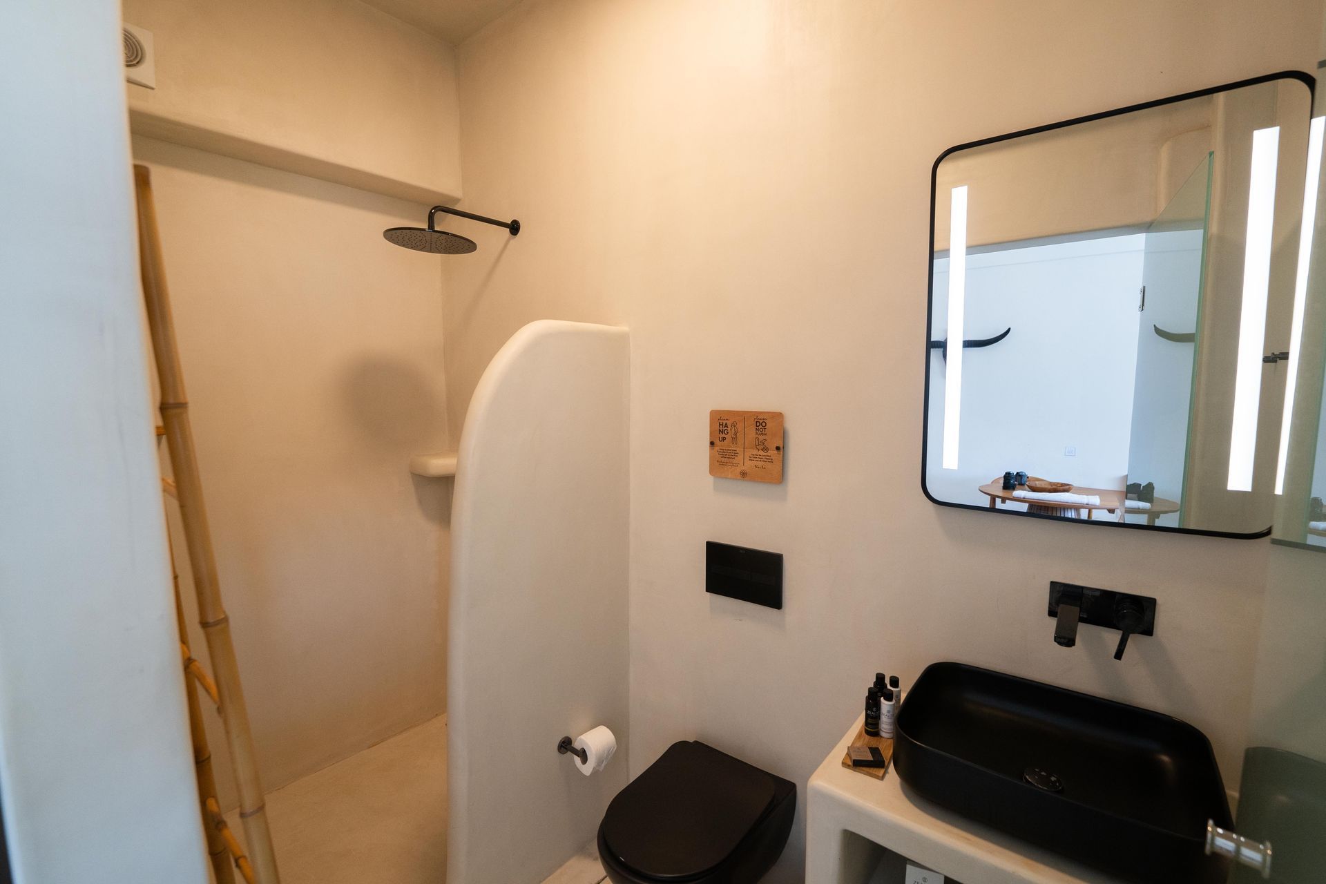 Small modern bathroom with a black toilet, sink, and shower.
