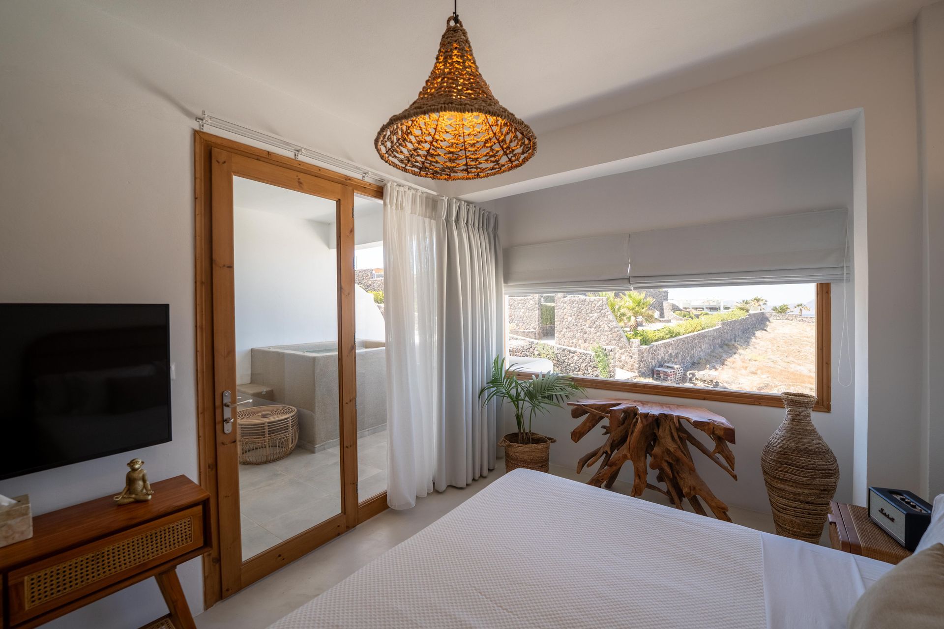 Bedroom with bed, wood accents, and window view of stone wall.