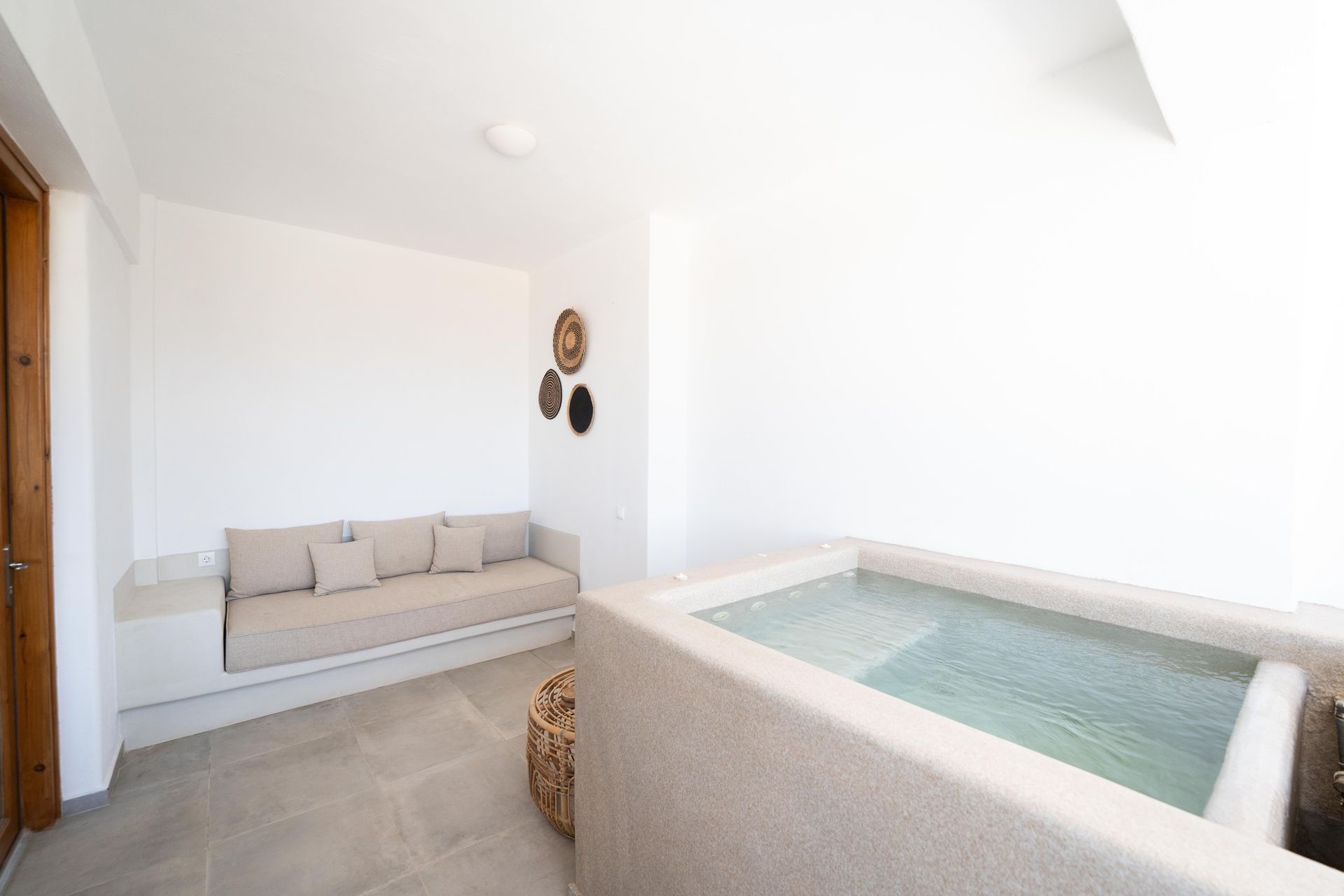 Bright white interior with built-in sofa, small spa pool, and wall decor.