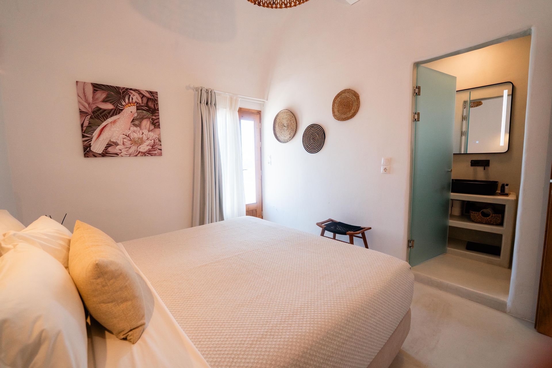 Bedroom with a bed, artwork, and a frosted-glass bathroom door.