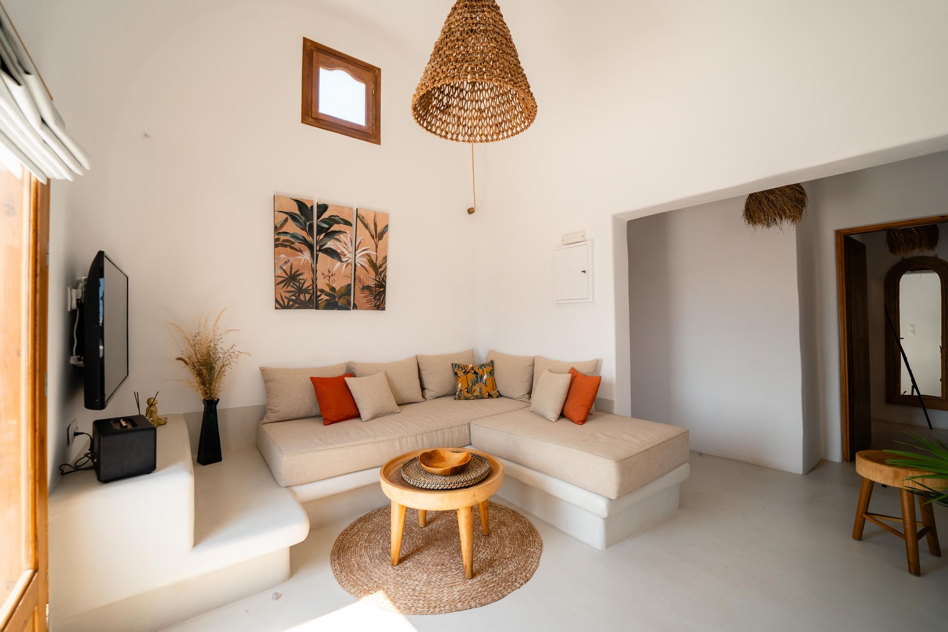 Bright living room with beige sectional sofa, wooden table, and woven pendant light.
