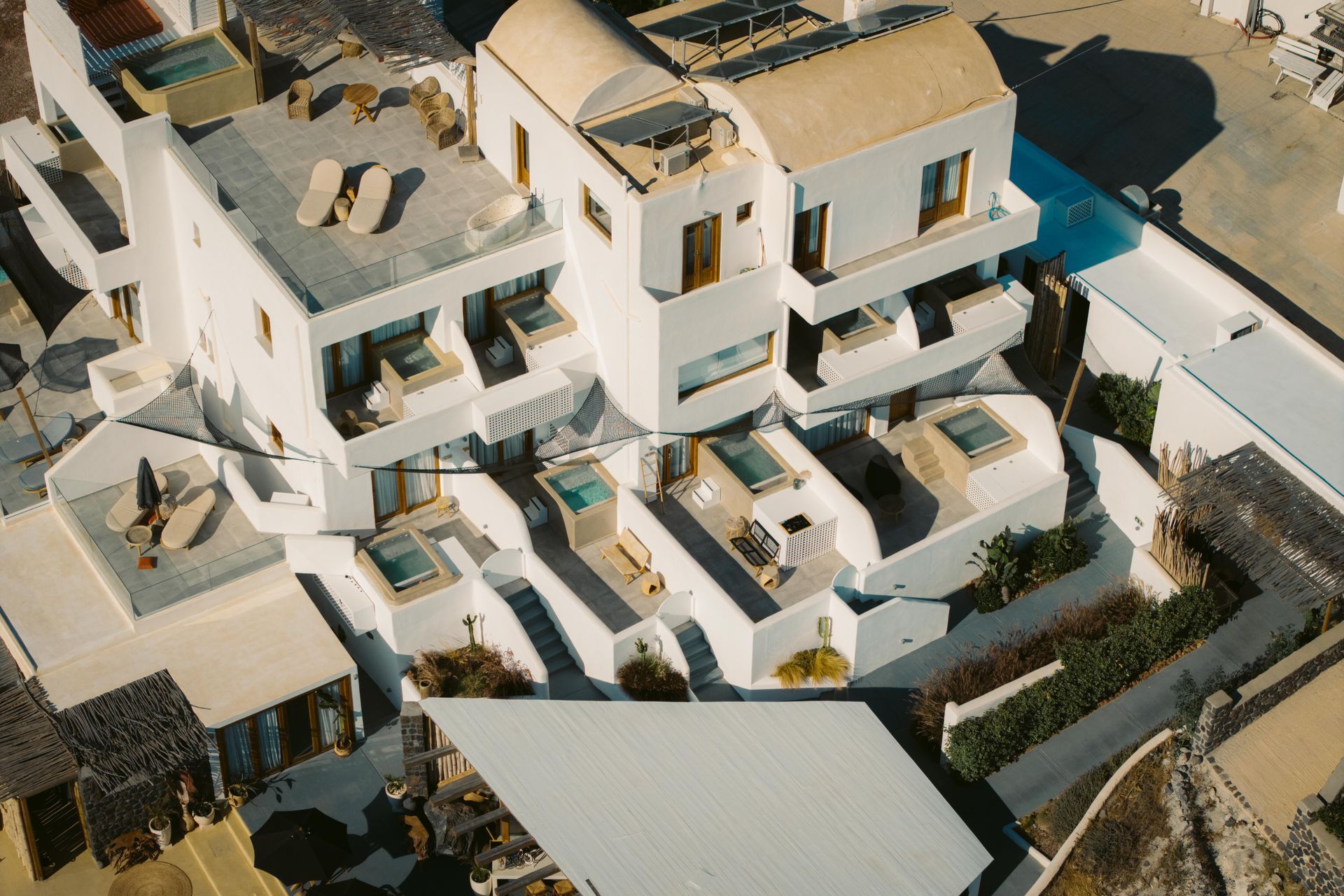 White buildings with flat roofs, pools, and terraces in a sunny setting.