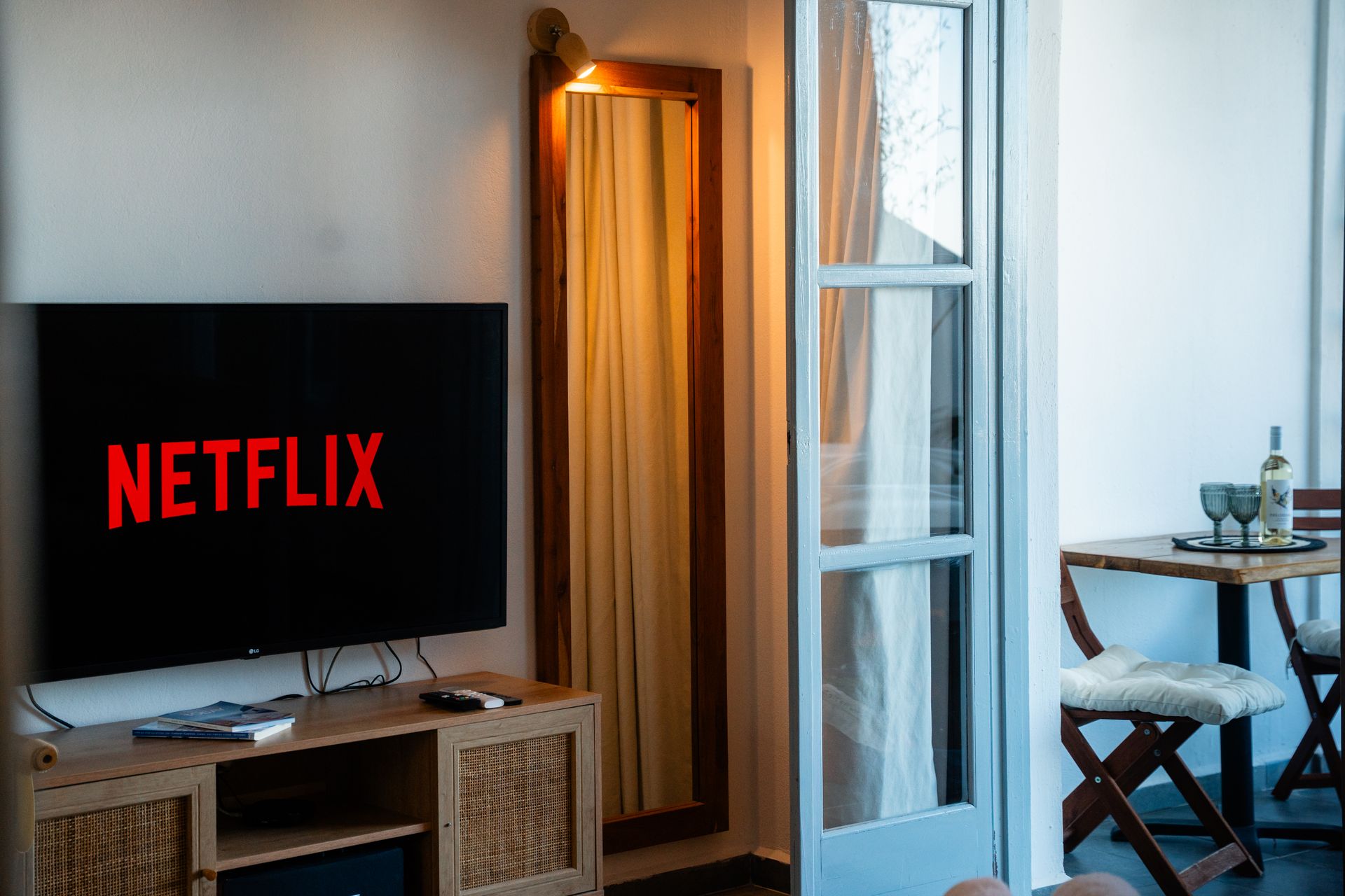 Netflix logo on a TV in a room with a mirror and a small balcony.