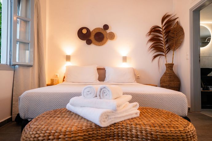 Bedroom with bed, decorative wall art, and a woven ottoman with towels.