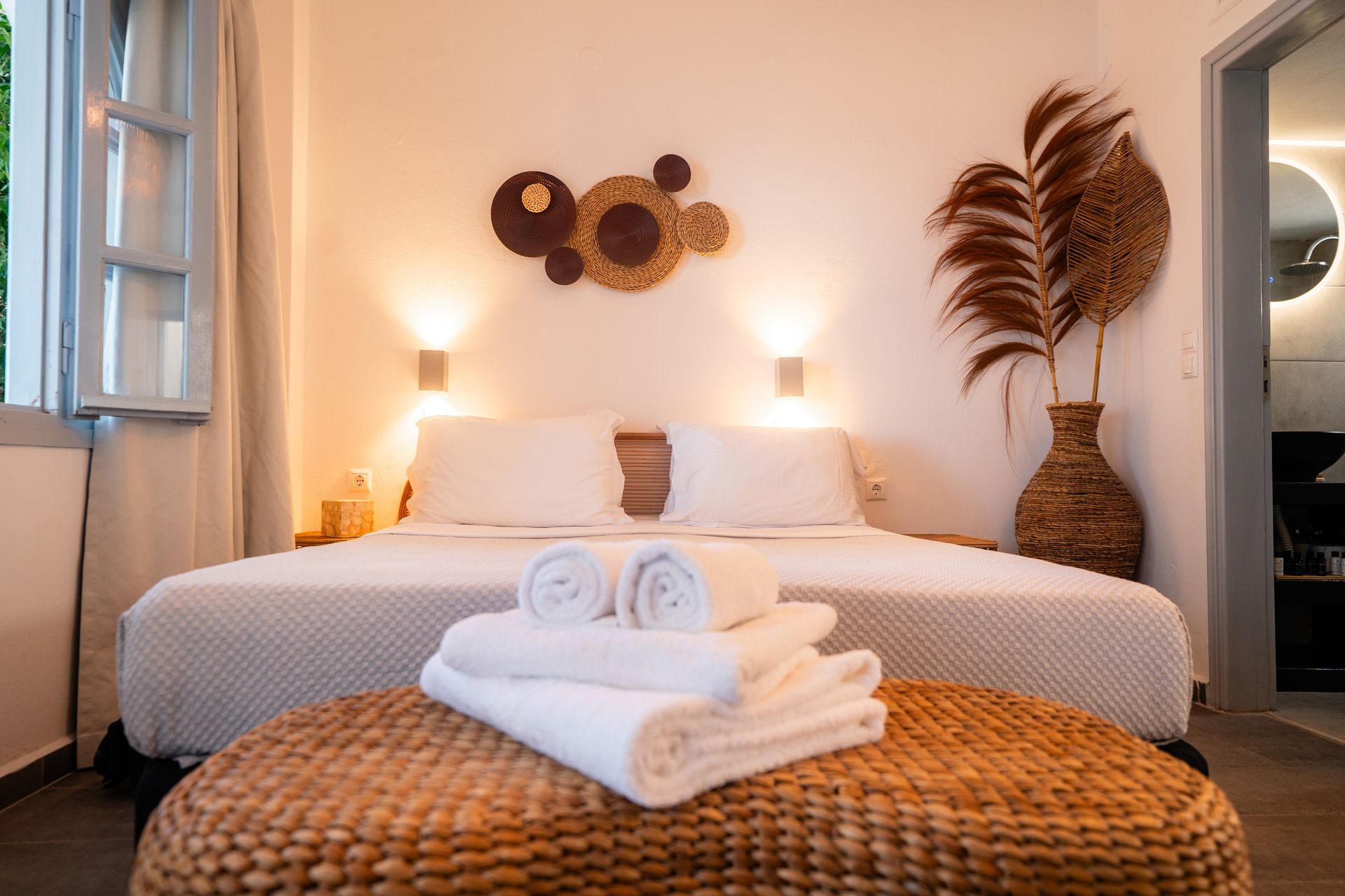 Bedroom with a bed, towels, decorative wall art, and a vase of tall grasses; light and airy.