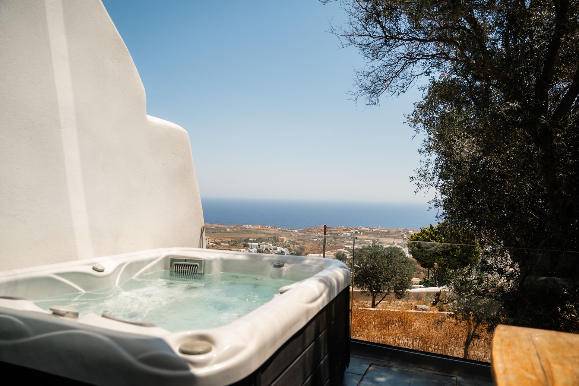 Hot tub overlooking the Aegean Sea, white buildings, and blue sky.