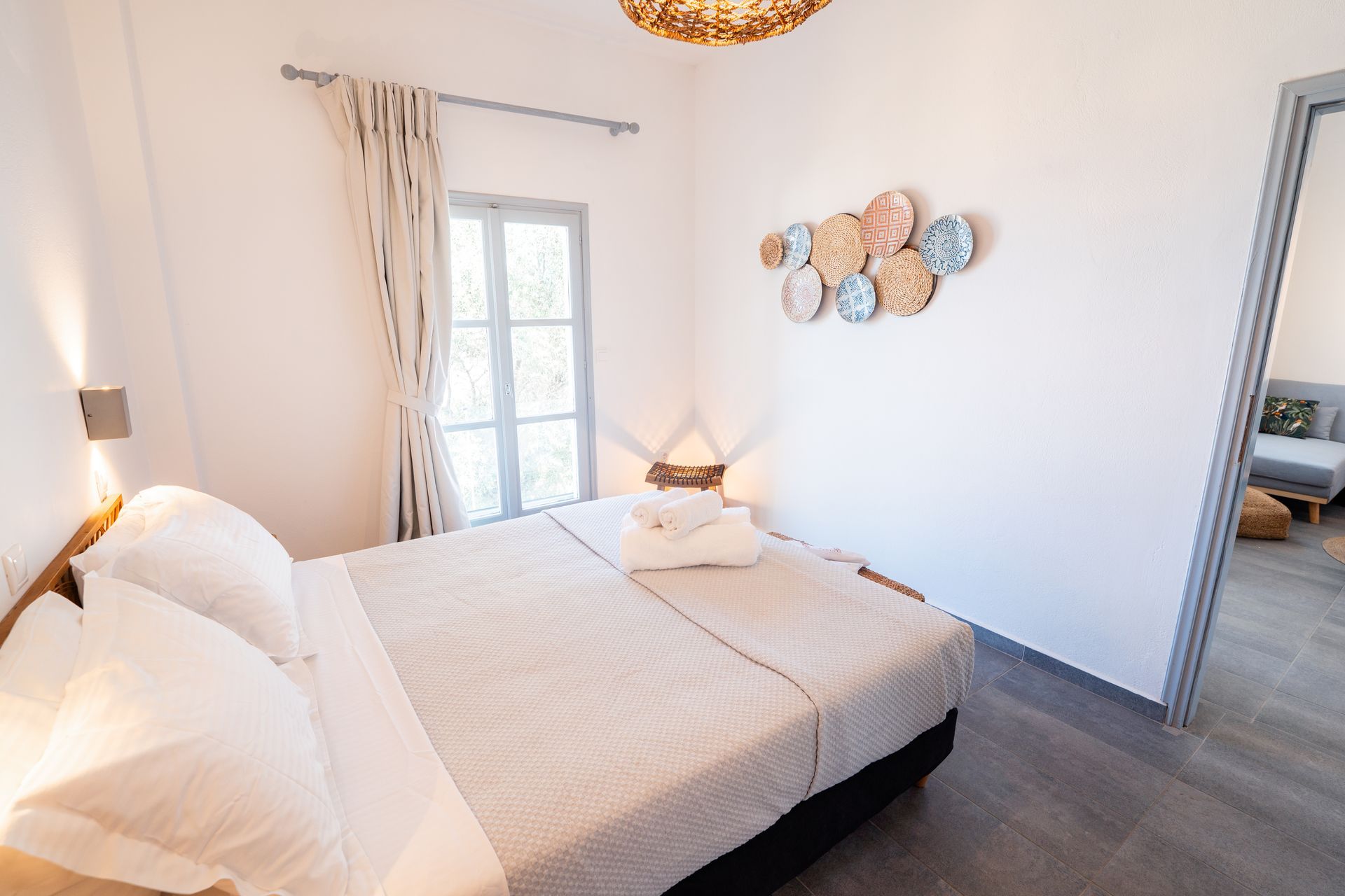 Bedroom with a bed, window, wall decor, and doorway to another room.