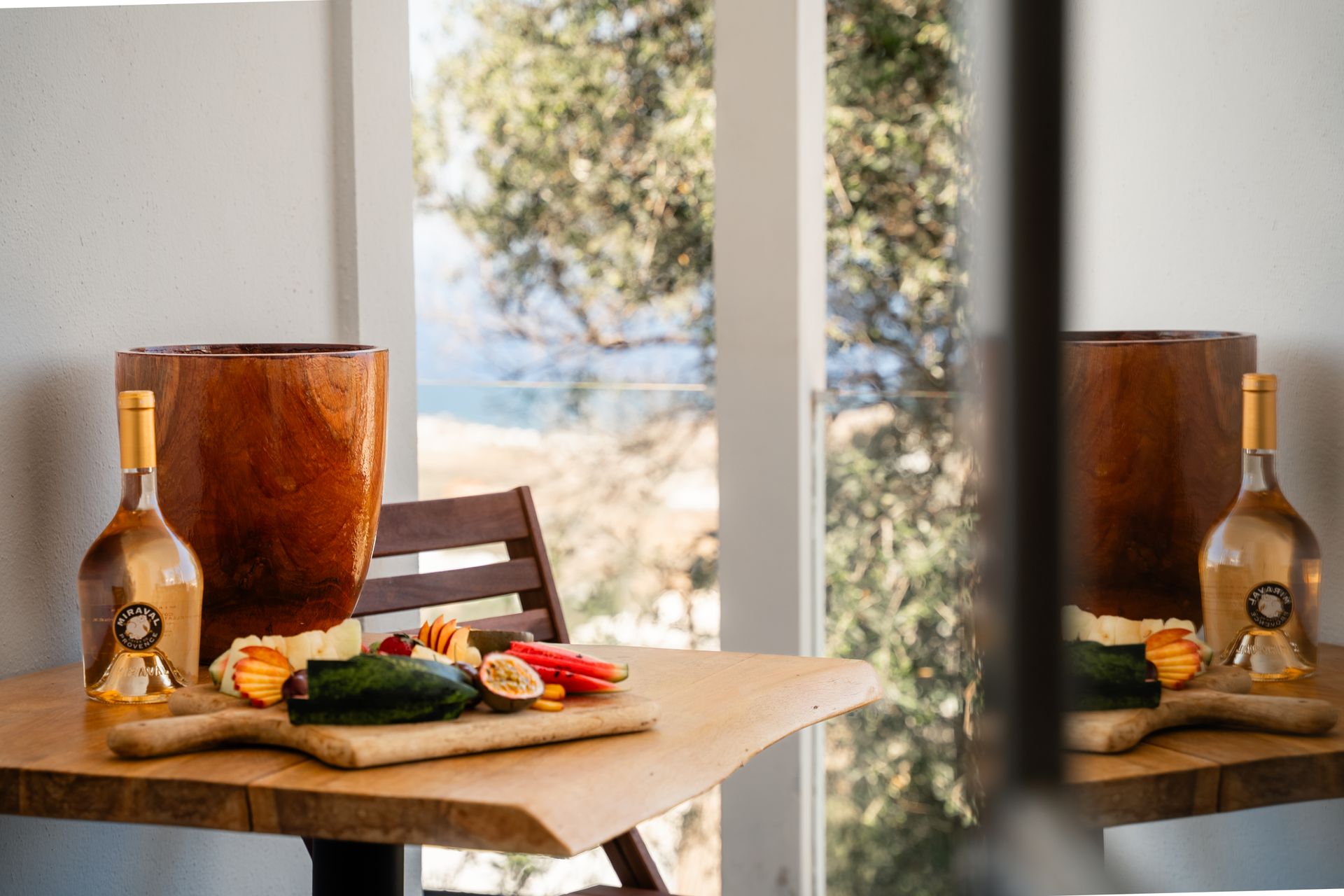 Wooden table with food and wine, looking out to a scenic view.