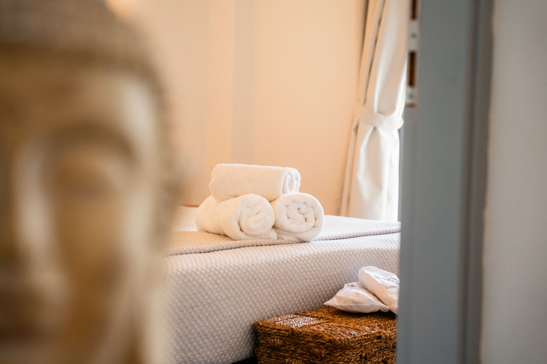 Massage table with folded white towels, neutral colors, serene spa setting.